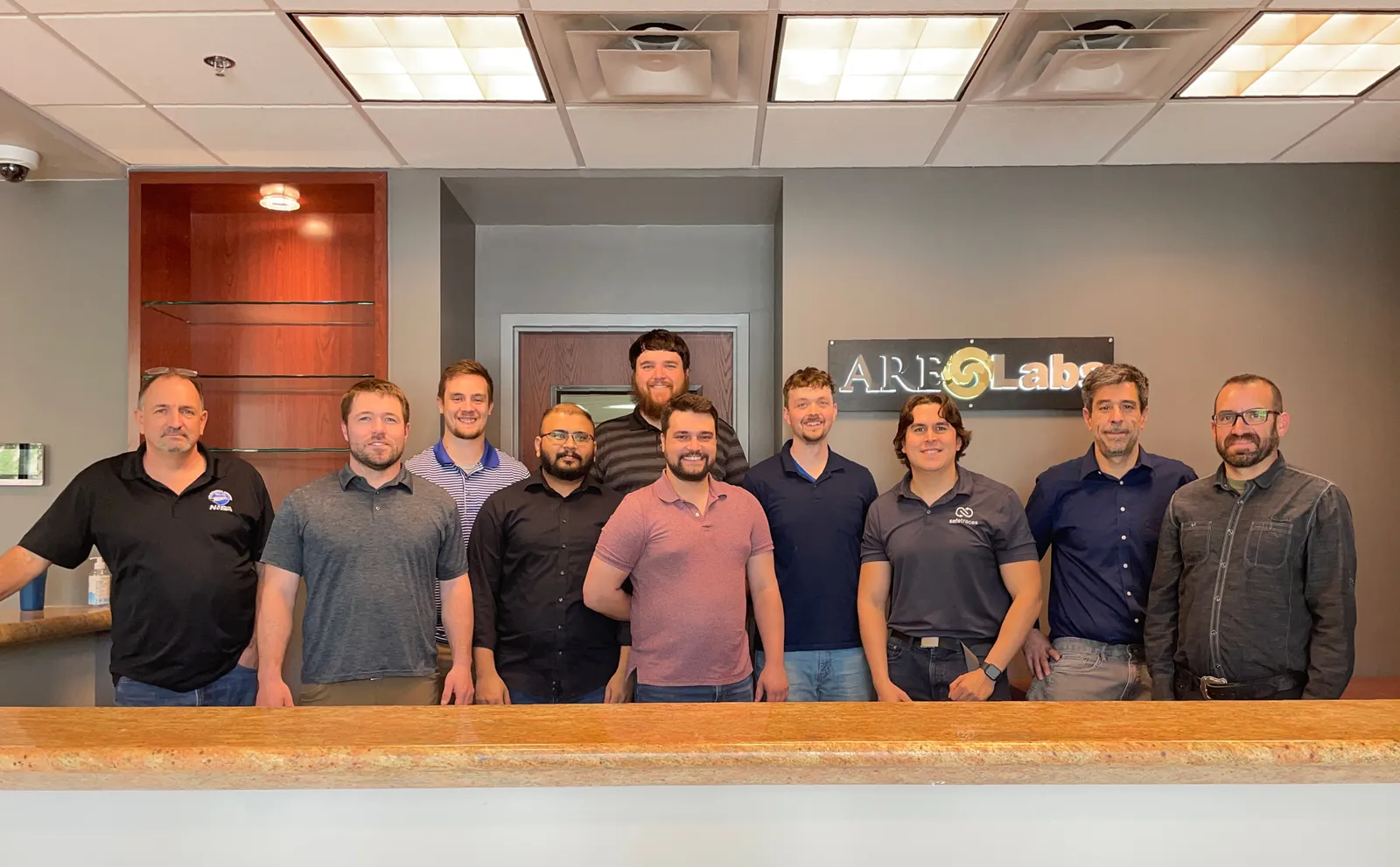 ARE Labs team group photo in the lobby with the company sign